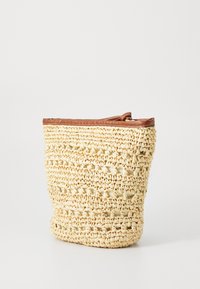 Vevd stråveske i en lys beige farge med brunt skinnkant. Har en teksturert overflate og en slapp, rund form.