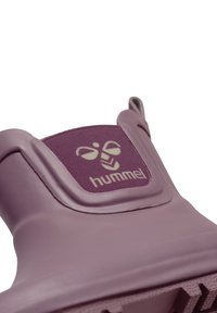 Chaussure en caoutchouc violet avec un design texturé, arborant une pièce en tissu emboutie avec le logo "hummel" et un graphique insectoïde.