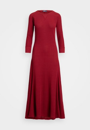 Robe longue rouge en tricot côtelé avec des manches trois quarts, décolleté en V et ourlet évasé, présentant une texture lisse et un design simple.