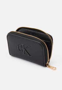 Black leather wallet with embossed "CK" logo, gold zipper, and textured fabric lining, featuring a compact rectangular design.
