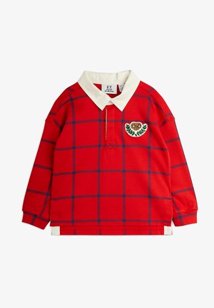 Punane pika varrukaga polo särk valge kraega, millel on sinine ruuduline muster ja tikandiga südametempel lehtede detailidega.