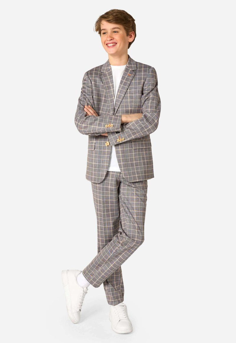 Blazer a quadri grigi e pantaloni abbinati, con dettagli gialli e blu. Indossato con una t-shirt bianca e sneakers bianche.