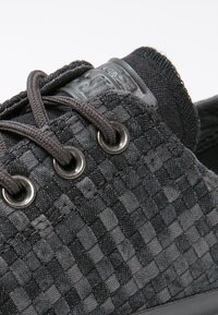 Černé tkané boty se zaoblenou špicí, šedými tkaničkovými očky a texturovanými akcenty. Disponují tmavým tónovým šitím a polstrovanou oblastí kolem kotníku.