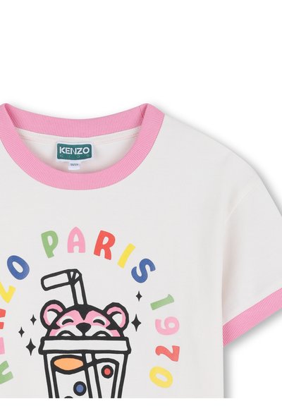 Biała koszulka z krótkim rękawem z różowym prążkowanym kołnierzem. Na przodzie kolorowa grafika przedstawiająca kubek z napojem i niedźwiedzia oraz napis "KENZO PARIS 1970".