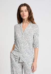 Pyžamový set s leopardím vzorem z lehké tkaniny; obsahuje košili s límečkem, dlouhými rukávy a knoflíkovými manžetami, doplněnou o odpovídající kalhoty.