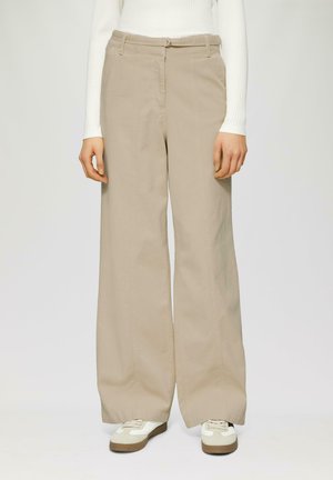 Beige wijde broek van katoen twill, met een hoge taille, riemlussen en zijzakken, gecombineerd met witte sneakers.