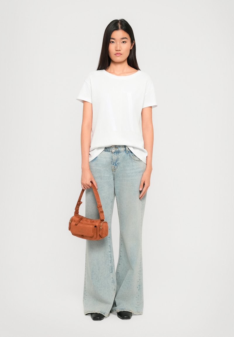 Hvid kortærmet t-shirt, lysvaskede vide jeans og en brun ruskinds håndtaske med lynlås og stropdetaljer, båret med sorte sko.