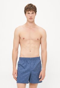 Pantaloni da bagno blu navy con vita elasticizzata, caratterizzati da un motivo a diamante. Realizzati in tessuto leggero, adatti per attività acquatiche.