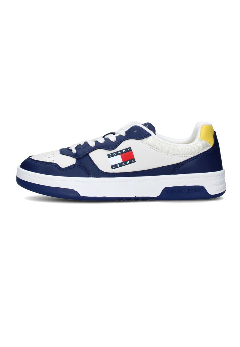 Sneakers bianchi in pelle con accenti blu navy, dotati di una toppa con logo blu e rosso, accentuazione gialla sul tallone e lacci bianchi, progettati per l'uso casual.