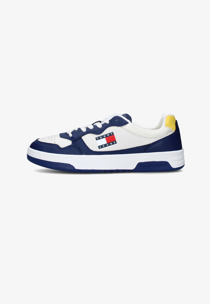 Sneakers bianchi in pelle con accenti blu navy, dotati di una toppa con logo blu e rosso, accentuazione gialla sul tallone e lacci bianchi, progettati per l'uso casual.
