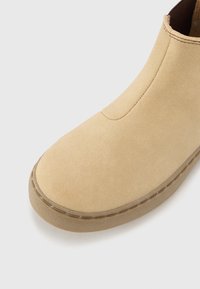 Beige ante čevlji do gležnjev z ovalnim nosom, elastičnim stranskim panelom in strukturiranim gumijastim podplatom, ki vsebuje vidne šive.