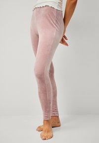 Zachte roze fluwelen leggings met een gladde textuur, een aansluitend ontwerp en een geschulpte tailleband, getoond met blote voeten.