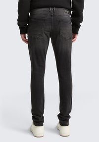Čierne džíny z denimu so slim fit strihom, päť vreciek a vyblednutým vzhľadom. Obsahujú jemné švy a stredne vysoký pás.
