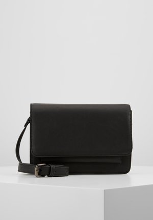 Bolso bandolera rectangular negro de cuero con solapa plegable y correa ajustable, exhibido sobre un pedestal blanco contra un fondo gris.