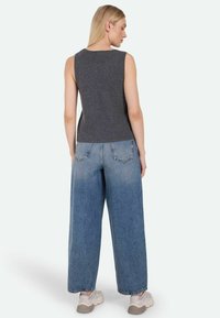 Gray sleeveless top paired with faded wide-leg blue jeans and light-colored sneakers, viewed from the back.