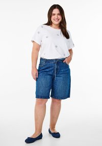 White short-sleeve t-shirt with small blue prints, paired with blue denim shorts featuring a drawstring waist and relaxed fit.