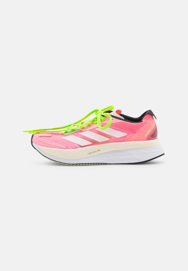 Chaussure de course rose avec des rayures blanches, des lacets vert fluo, une semelle intermédiaire blanche épaisse et une semelle extérieure noire, présentée sur fond blanc.