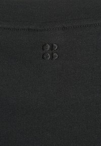 Zwarte gestreepte stof met een close-upweergave, voorzien van een klein geborduurd logo in een donkerdere tint, dat textuur en ontwerpdetails aanduidt.