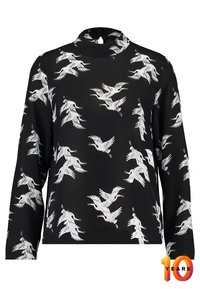 Svart långärmad blus med hög halsringning, med ett vitt mönster av tranar över hela plagget. Slät tygkvalitet med avslappnad passform.