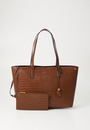 Pruun krokodillimustriga kott kahe käepidemega, kuldse tooni riistvara ja sobiva eraldatava tõmblukuga rahakotiga ees.