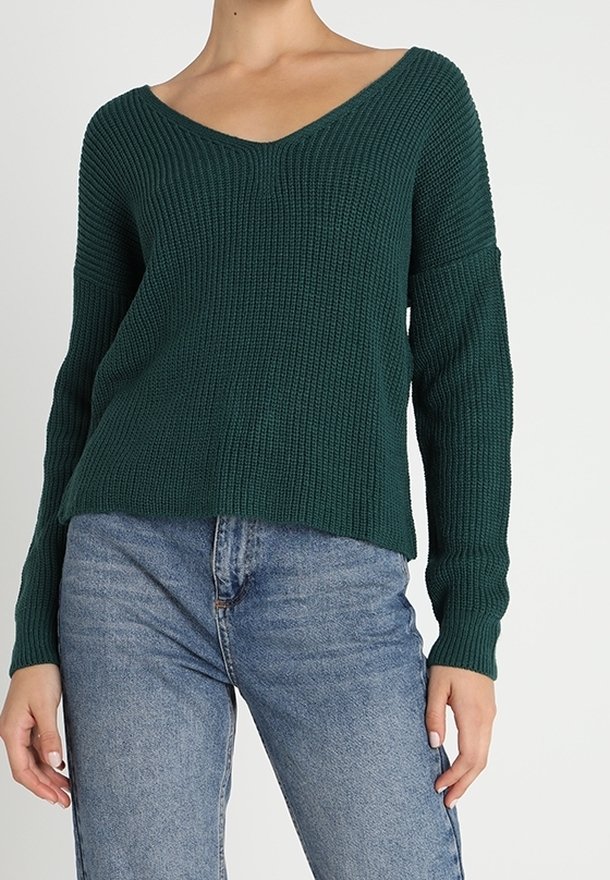 Pull vert en tricot avec col en V, manches longues et coupe décontractée. Le tissu texturé présente des détails côtelés et un ourlet court.