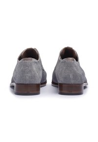 Graue Stoffschuhe mit strukturiertem Finish, kontrastierenden braunen Lederelementen und einem Holzabsatz. Verfügt über runde Zehen und Zuglaschen hinten.