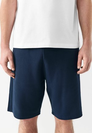 Pantalones cortos azul marino hechos de una tela texturizada, con una cinturilla elástica y bolsillos laterales, diseñados para la comodidad y la movilidad.