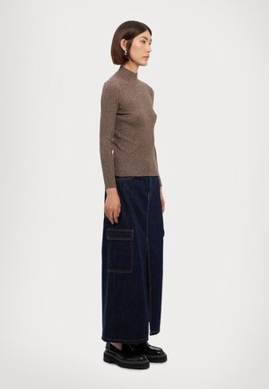 Brown ribbed knit turtleneck paired with a long, dark denim skirt featuring side pockets and a front slit. Worn with black platform shoes.