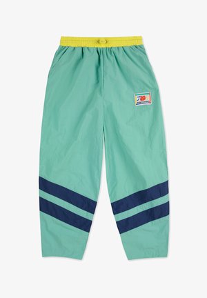 Pantalones de chándal ligeros en verde menta con un patrón de rayas en azul marino, cintura elástica amarilla y una etiqueta en el muslo izquierdo.