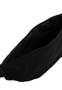 Pochette nera con zip e dettaglio a nodo, parzialmente aperta per mostrare il vano principale vuoto e la tasca interna.