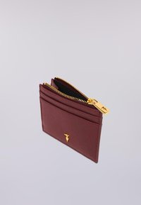 Bordeaux lederen kaart houder met een gouden rits, vier kaartsleuven en een gouden logo-accent aan de voorkant, met een textuur oppervlak.