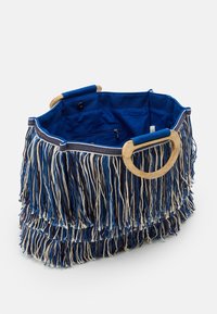 Fransväska med en blå och beige färgpalett, med ett runt trähandtag, textilmaterial och ett fodrat inre med en ficka med dragkedja.