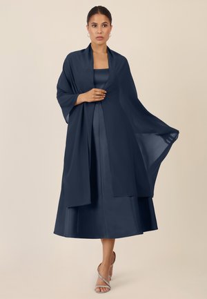 Abito a strati blu navy con corpetto in satin, sovrapposizione trasparente fluida e maniche larghe. Completato da sandali alti argentati con cinturini.