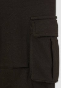 Czarna tkanina bawełniana o gładkiej fakturze, z kieszenią z klapą po boku. Projekt podkreśla minimalistyczny styl i czyste linie.