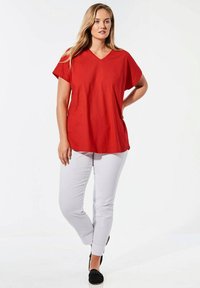 Rode kortefitted V-hals T-shirt, losse pasvorm, gecombineerd met witte slim-fit broek en zwarte instap schoenen. Gladde stof, casual ontwerp.