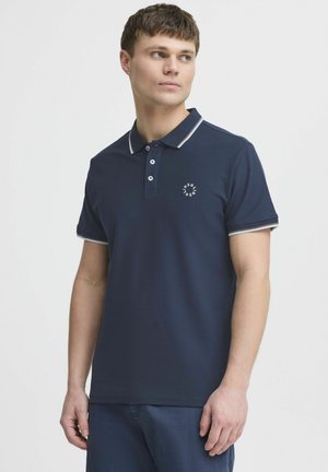 Marineblauwe poloshirt met een kraag, drie knopen en lichtgrijze afwerking op de mouwen. Heeft een klein logo op de borst. Zachte stoftextuur.