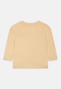 Langärmeliges, hellbeiges Oberteil aus weichem Baumwollstoff, Rundhalsausschnitt und abgesteppten Säumen, mit einfachem, ungeschmücktem Design.