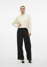 Felpa crema con una vestibilità rilassata, orlo a coste e maniche lunghe abbinata a pantaloni neri a gamba larga con vita alta e tacchi a punta neri.