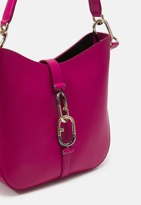 Roze leren schoudertas met een gladde textuur, gestructureerde vorm, goudkleurige hardware en een kenmerkende dubbele sluiting.