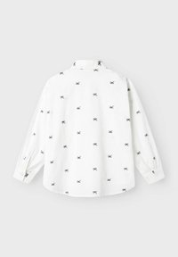 Camisa blanca de manga larga con un estampado disperso de lazo en color marino, puños abotonados y un diseño de cuello clásico. La tela parece suave y ligera.
