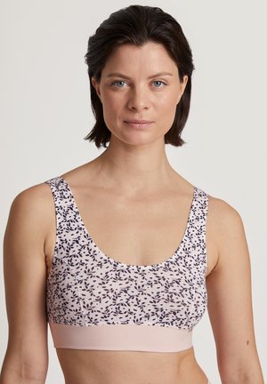 Lichtroze sport-bh met een bloemmotief in donkerblauw, met een naadloos ontwerp en brede bandjes voor comfort. Zachte stoftextuur.