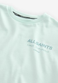 Mėtos žalumos marškinėliai, pagaminti iš švelnios medvilnės; turi apvalų iškirpimą, trumpus rankovėles ir užrašą "ALLSAINTS" su tekstu įvairiomis raidėmis.