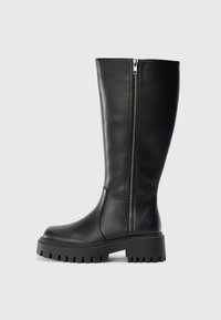 Čierne kožené čižmy po kolená so bočným zipsom, textúrovaný povrch, zaoblená špička a masívna gumová podrážka s segmentovým vzorom.