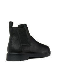 Botas Chelsea de cuero negro con paneles laterales elásticos, un acabado texturizado y una suela de goma plana con un ligero tacón.