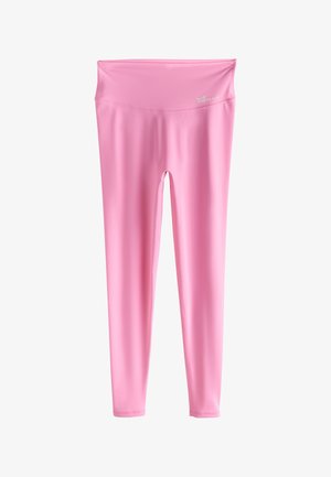 Roosades spordiriietes naine kõnnib tenniseväljakul kerge jakiga üle õlgade ja valgete tossudega.