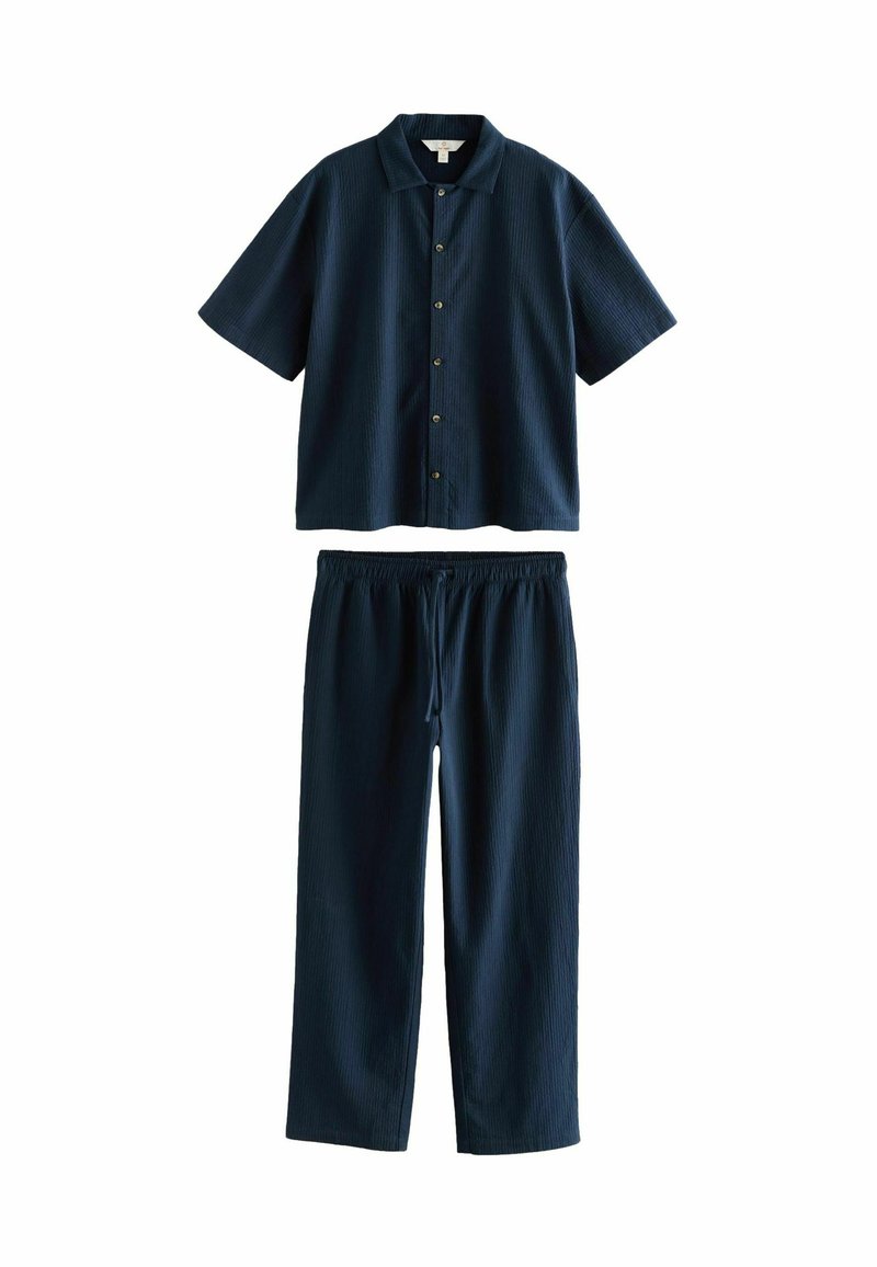 Tengerész kék, rövid ujjú ing, gombos elülső résszel, valamint azonos színű, rugalmas derékpántos nadrággal, texturált anyagból készült és laza szabású.
