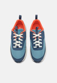 Blue and teal mesh athletic shoes with white laces, orange interior, pull tab on heel, and rubber outsole. Textured surface and rounded shape.