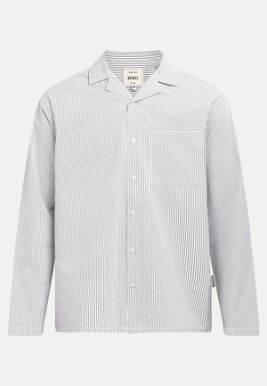 Košeľa s dlhým rukávom na gombíky s bielymi a čiernymi zvislými pruhmi a jedným náprsým vreckom na ľavej strane.