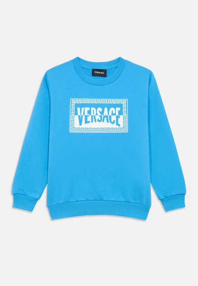 Sweat-shirt bleu vif à manches longues avec poignets et ourlet côtelés, avec un logo Versace blanc dans un cadre rectangulaire décoratif sur la poitrine.