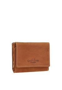 Compact brown leather wallet with visible stitching and embossed "Gusti Leder studio" logo on the front flap, closed and folded.